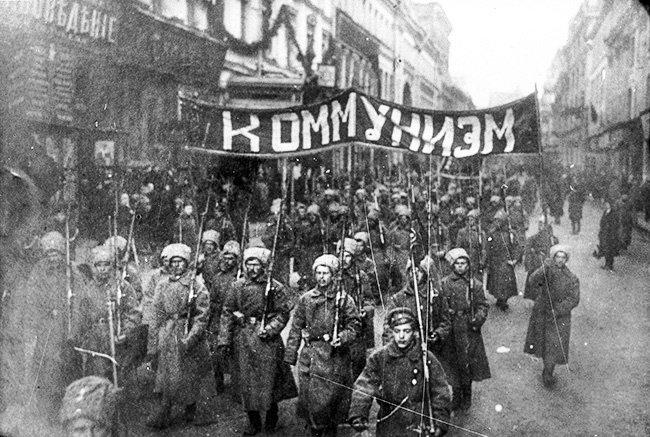 Armed soldiers carry a banner reading Communism Moscow Russia October 1917RESIZE